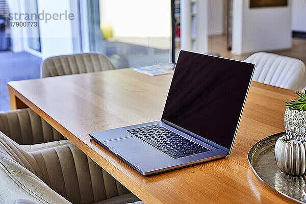Laptop on wooden dining table at home