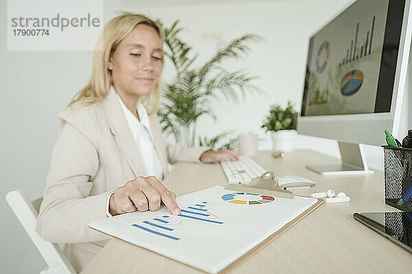 Geschäftsfrau arbeitet am Schreibtisch im Büro an einem Diagramm
