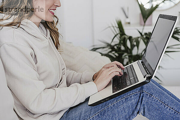 Lächelnde Frau  die zu Hause auf dem Laptop tippt