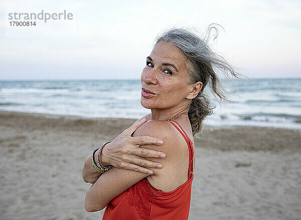 Ältere Frau umarmt sich am Strand