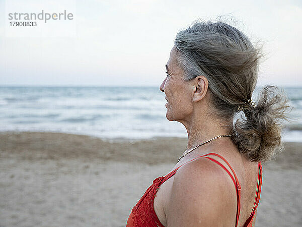 Nachdenkliche Frau mit grauen Haaren am Strand