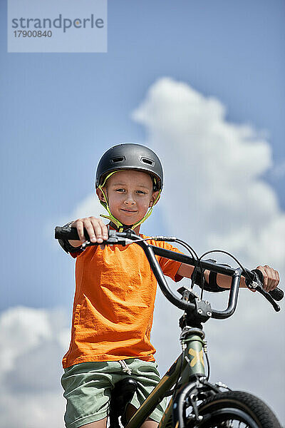 Junge mit Helm sitzt auf einem BMX-Fahrrad