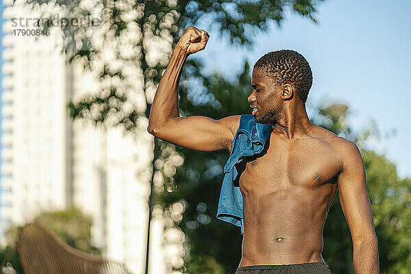 Hemdloser Mann lässt an einem sonnigen Tag Muskeln spielen