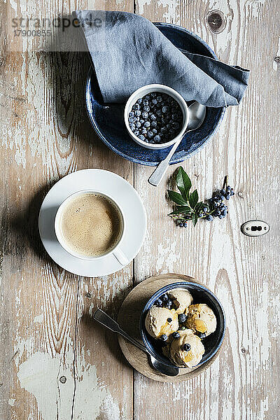 Tasse Kaffee  frische Blaubeeren und eine Schüssel hausgemachtes Erdnusseis