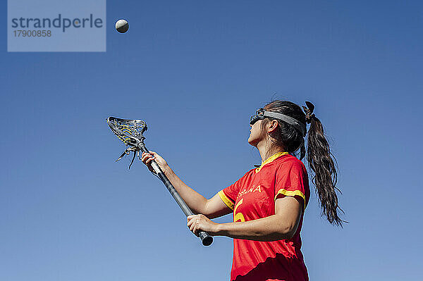Athlete playing lacrosse under blue sky
