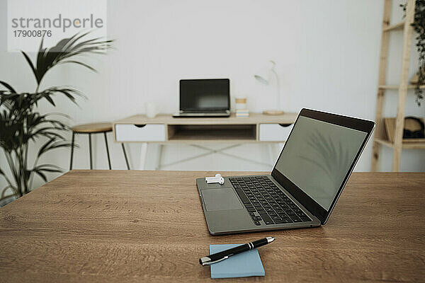 Laptop mit Klebezettel und Stift auf dem Tisch im Büro