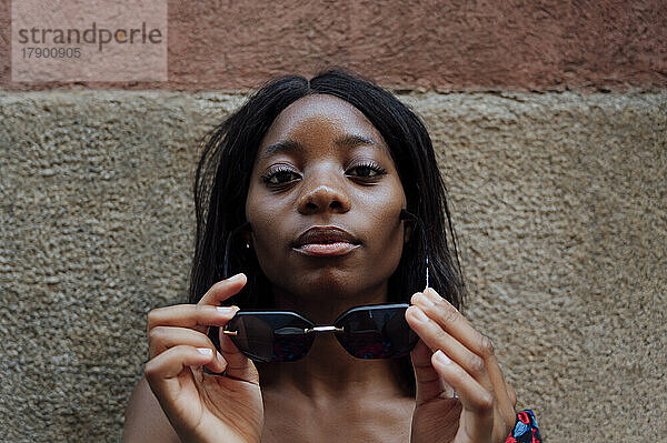 Junge Frau mit Sonnenbrille vor der Wand