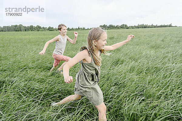 Happy siblings running on grass field