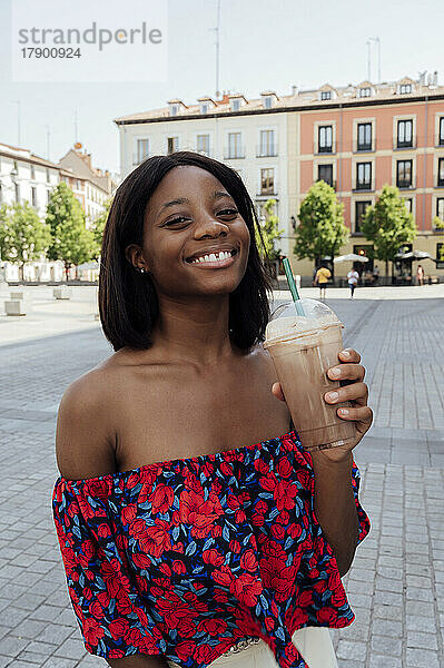 Glückliche Frau hält Einwegkaffeetasse auf der Straße