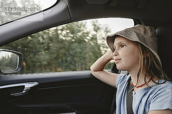 Cute girl wearing hat traveling in car
