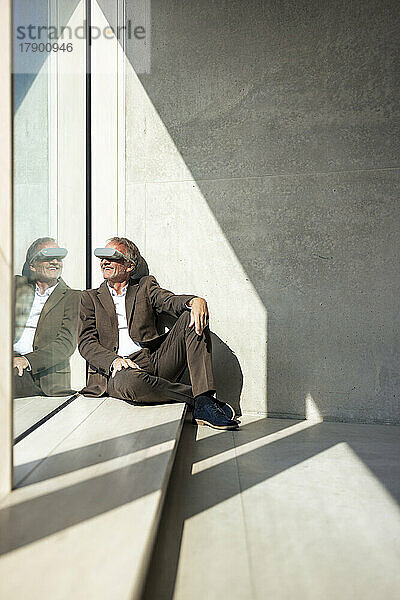 Lächelnder Geschäftsmann mit futuristischer Brille am Fenster im Büro