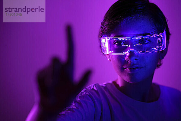 Lächelndes Mädchen mit Smart-Brille gestikuliert vor violettem Hintergrund