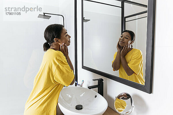 Woman looking at herself in bathroom mirror