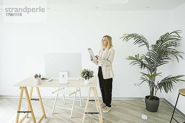 Geschäftsfrau steht mit Tablet-PC im Büro