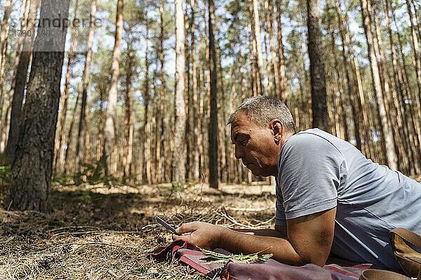 Reifer Mann benutzt Smartphone im Wald