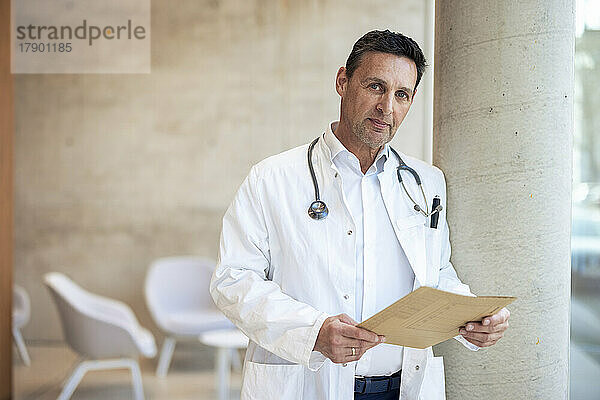 Selbstbewusster Arzt mit Berichtsdokument im Krankenhaus