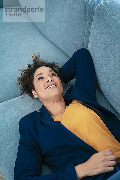 Thoughtful businesswoman relaxing on sofa at workplace