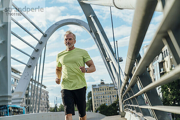 Mann joggt auf Hängebrücke in der Stadt