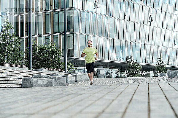 Reifer Mann joggt auf Fußweg in der Stadt