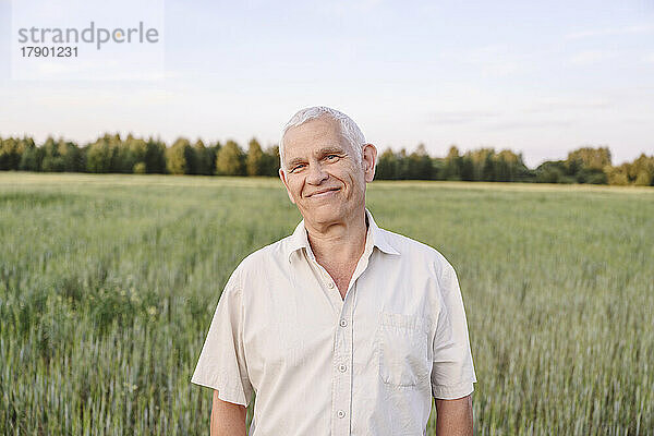 Lächelnder älterer Bauer steht auf dem Bauernhof