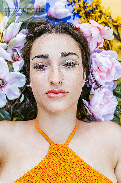 Traurige Frau liegt auf Blumen mit tropfenförmigem Aufkleber