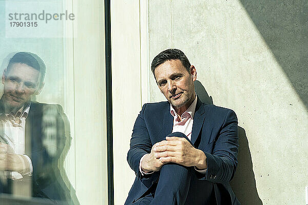 Reifer Geschäftsmann sitzt am Fenster im Büro