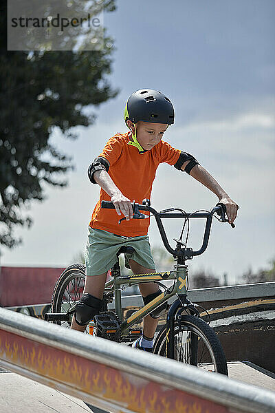 Entschlossener Junge mit Helm auf BMX-Fahrrad