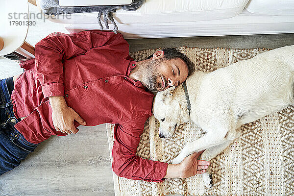 Mann und Hund schlafen zu Hause zusammen auf dem Teppich