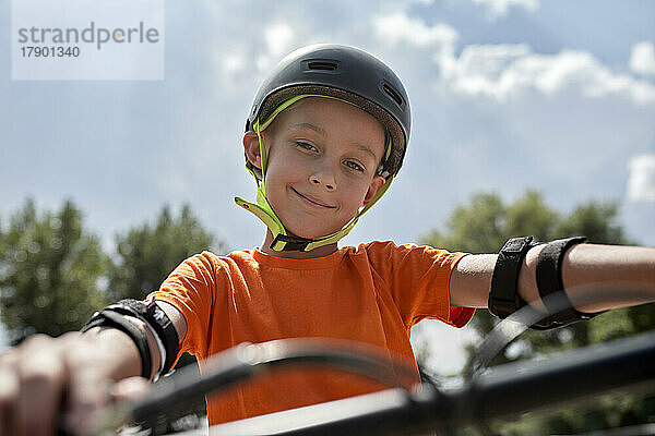Lächelnder Junge mit Fahrradhelm und Schutzausrüstung