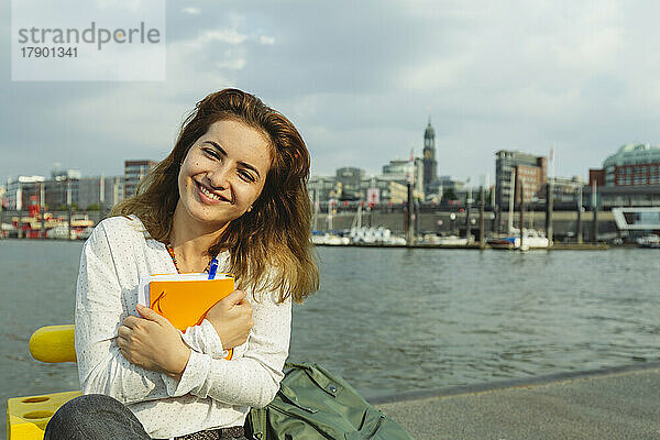 Glückliche Frau mit Tagebuch im Hamburger Hafen