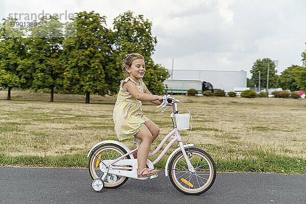 Lächelndes Mädchen  das im Park Fahrrad fährt