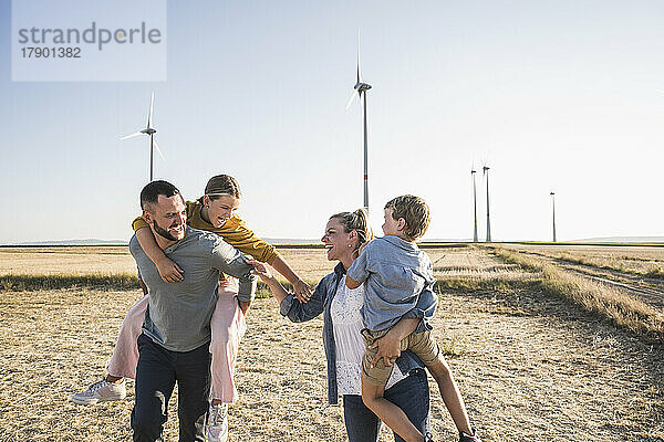 Selbstbewusste Familie steht Händchen haltend im Windpark