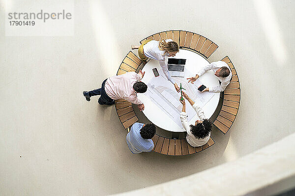 Geschäftskollegen  die eine Windkraftanlage planen  sitzen auf einem Tisch in der Bürolobby