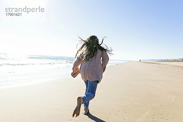 Mädchen läuft an einem sonnigen Tag am Strand