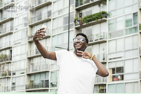 Glücklicher Mann gestikuliert und macht ein Selfie mit dem Handy