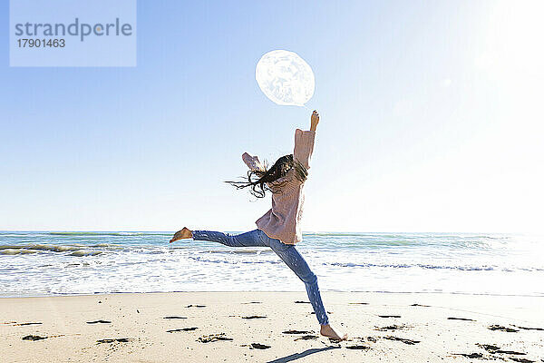 Mädchen springt mit Ballon am Strand