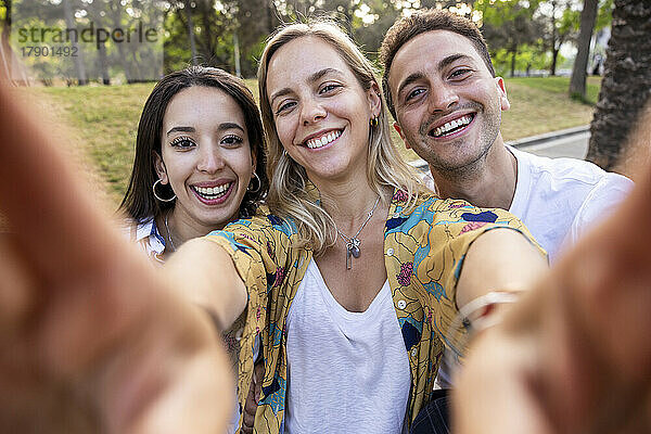 Glückliche Frau macht Selfie mit Freunden im Park
