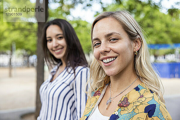 Happy blond woman with friend at park