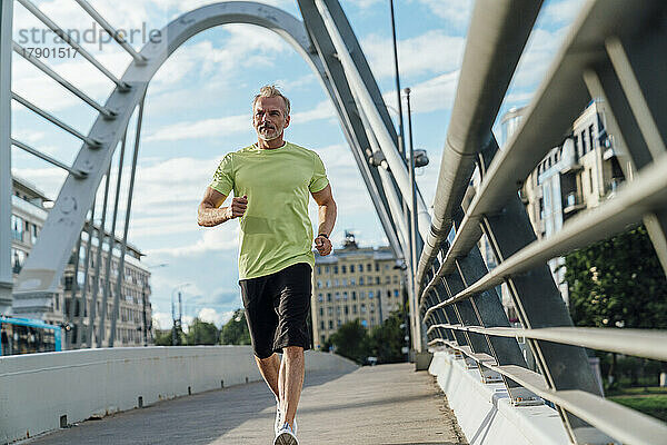 Reifer Mann läuft auf Brücke in der Stadt