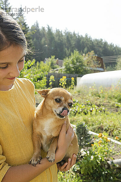 Lächelndes Mädchen mit Hund im Garten