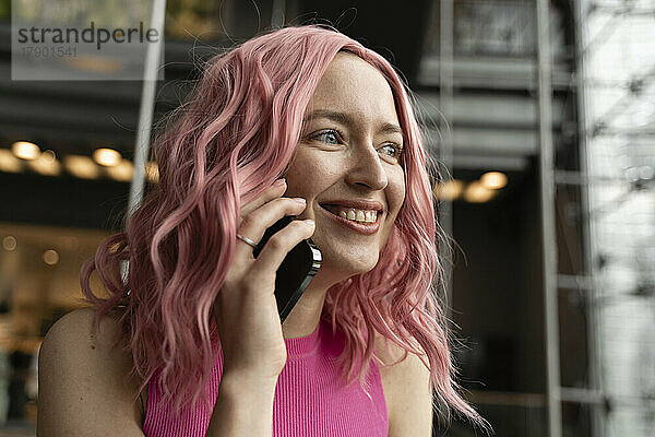 Glückliche Frau mit rosa Haaren  die mit dem Handy spricht