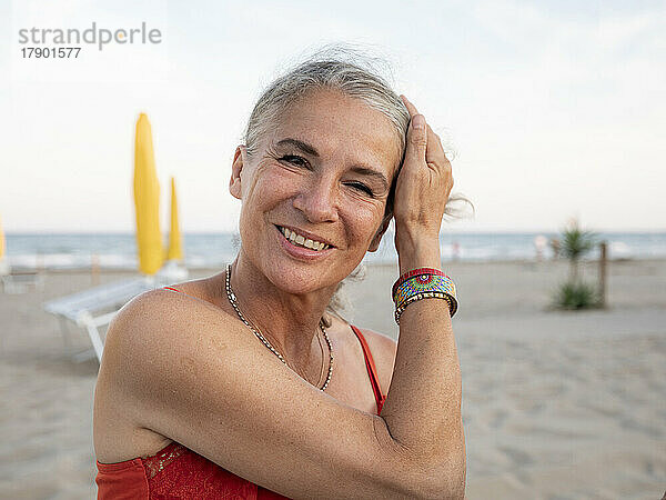 Glückliche ältere Frau mit grauen Haaren am Strand