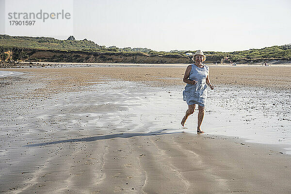 Aktive ältere Frau läuft an einem sonnigen Tag am Strand