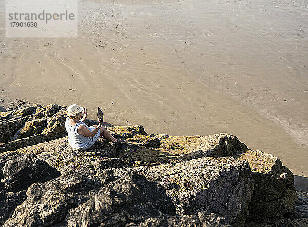 Ältere Frau spricht am Strand per Videoanruf über einen Tablet-PC