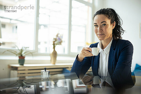 Lächelnde Geschäftsfrau beim Kaffee am Tisch