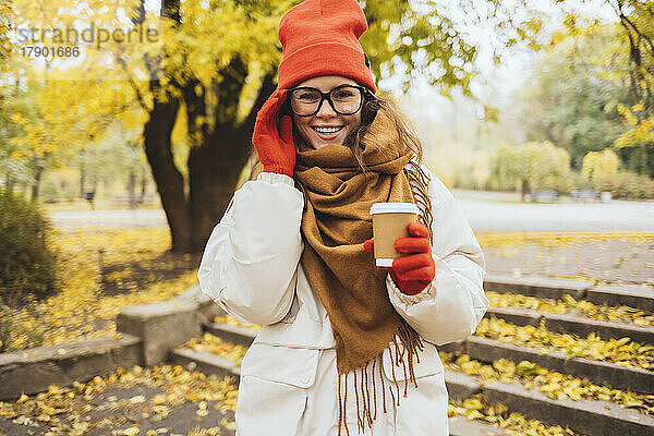 Glückliche Frau mit Brille und Einwegbecher im Park