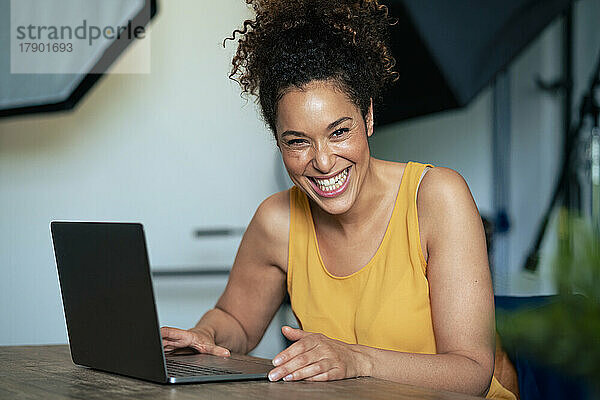 Geschäftsfrau mit Laptop lacht am Tisch im Büro