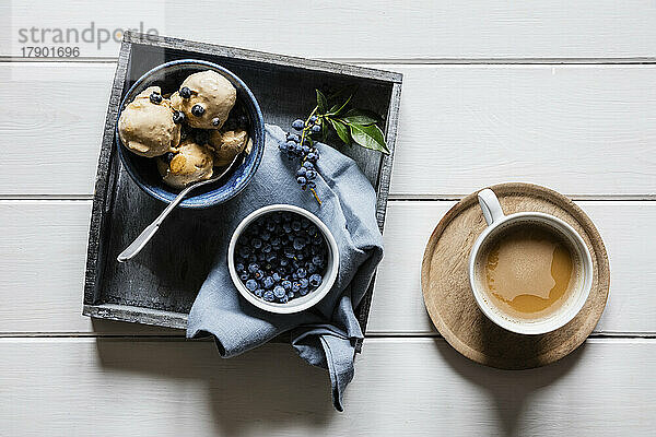 Cup of coffee and tray with fresh blueberries and homemade peanut ice cream