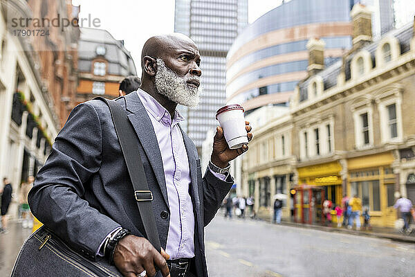 Nachdenklicher Geschäftsmann trinkt Kaffee auf der Stadtstraße