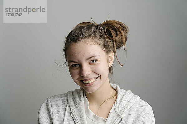 Lächelnde junge Frau vor grauem Hintergrund